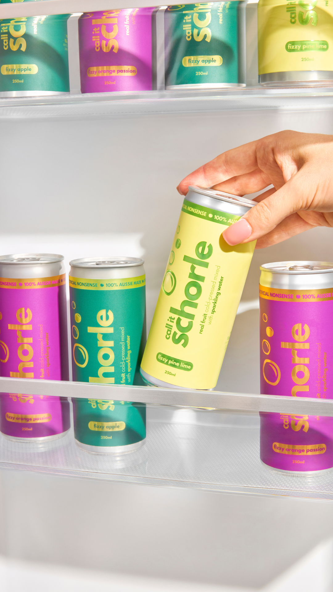 A brightly lit fridge stocked with colorful cans of schorle, a sparkling cold-pressed juice made from real fruits and veggies. 

